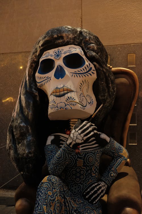 Person in Traditional Scary Mask and Costume Sitting on Chair