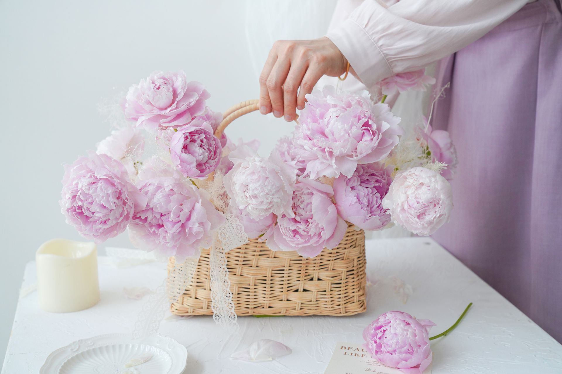 A delicate floral arrangement of pink peonies in a wicker basket, highlighting elegance and natural beauty.