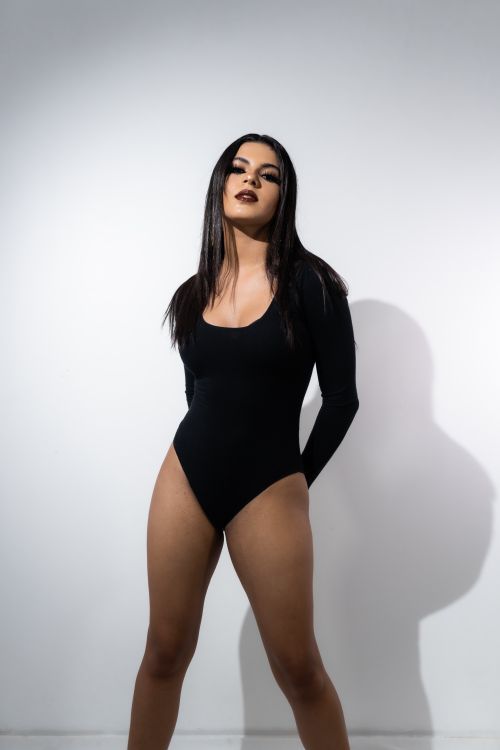 Free Stylish studio portrait of a confident woman posing in a sleek black bodysuit. Stock Photo