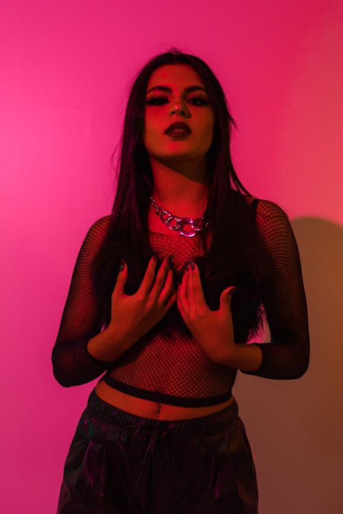 Seductive Woman in a See-Through Blouse on Pink Background 
