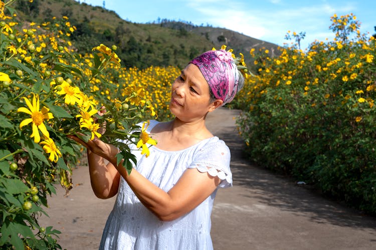 Woman Touching Flowers On The Roadside 