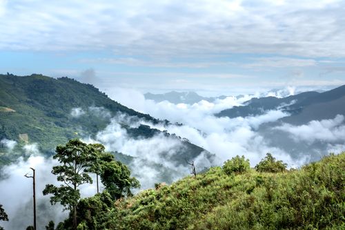 Free Serene mountain landscape with rolling hills and clouds below a partly cloudy sky. Stock Photo