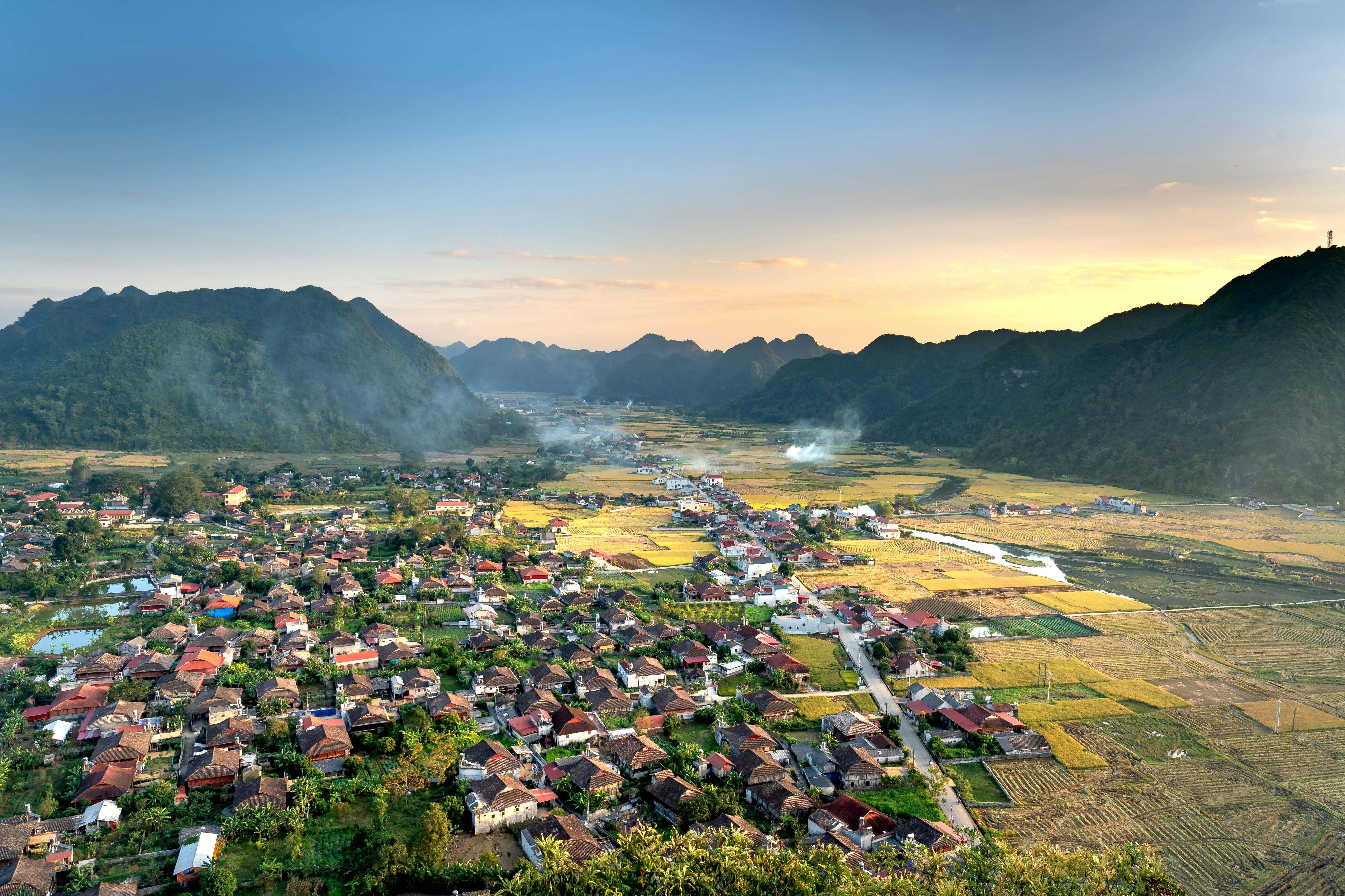 Scenic aerial view of Bac Son Valley, Vietnam, capturing houses and lush fields at sunset.