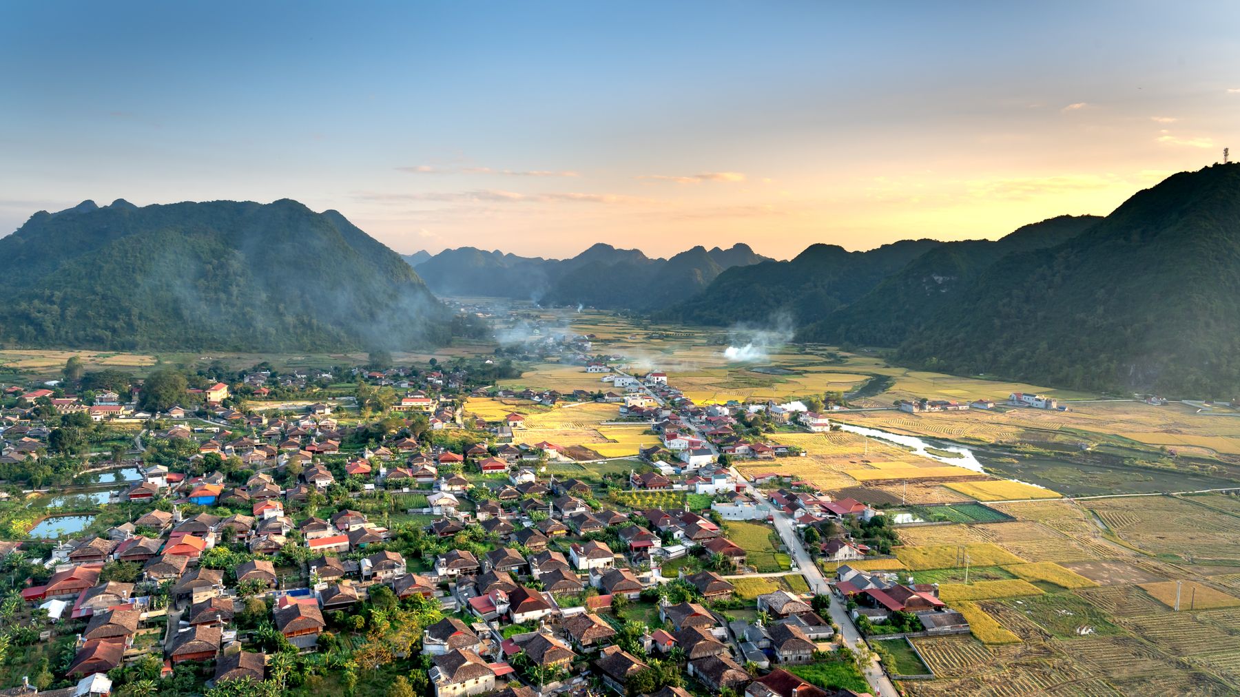Scenic aerial view of Bac Son Valley, Vietnam, capturing houses and lush fields at sunset.