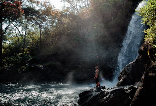 Man Standing Near Majestic Waterfall