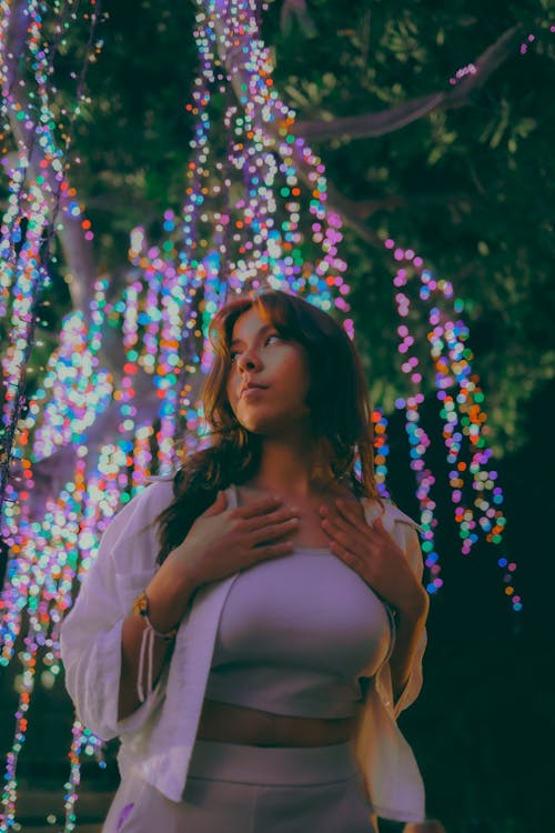Woman Posing under Decorated Tree at Night