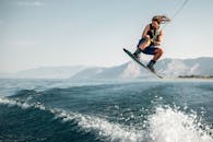 一名年轻人在海浪上的尾水板上跳高，展示了极限水上运动技能