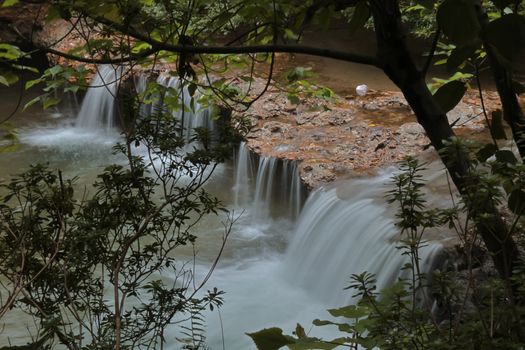 Peaceful waterfall flowing through lush green forest. Perfect for nature enthusiasts.
