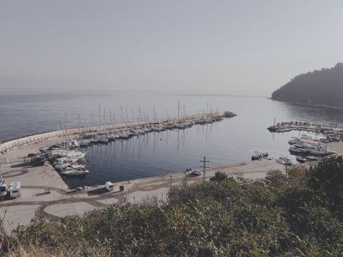 Free Tranquil harbor scene with yachts and clear sea at sunrise, perfect for peaceful vacation vibes. Stock Photo