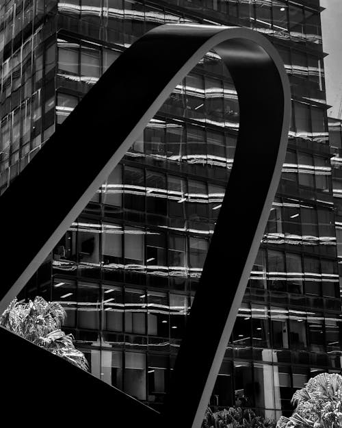 Black and White Photo of a Sculpture and a Modern Building Facade in City 