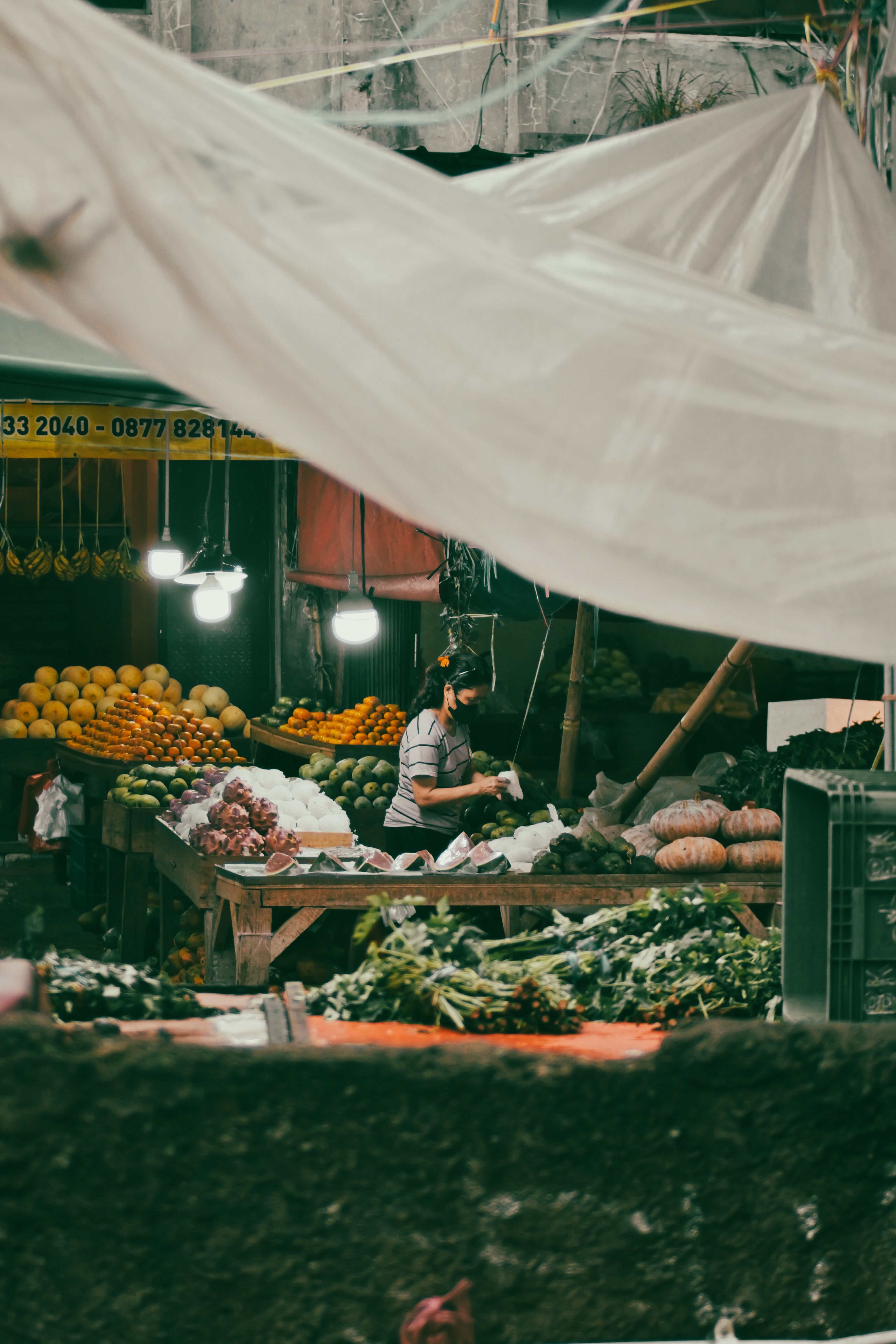 Seorang penjual menyediakan berbagai buah dan sayuran segar di pasar Indonesia.