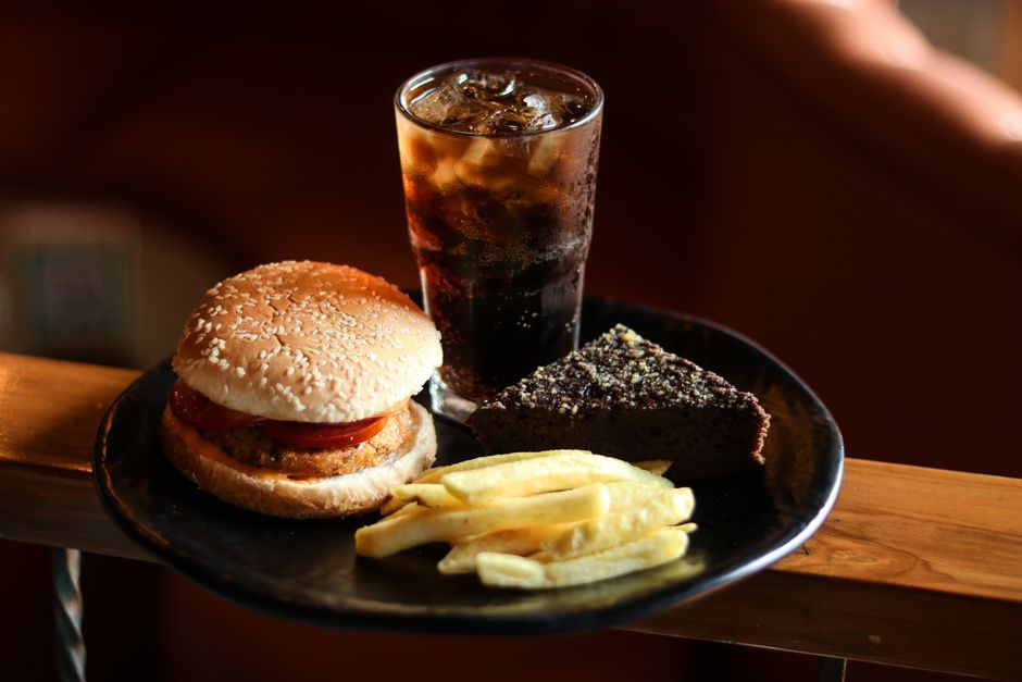 Gourmet burger with fries, brownie, and soda on a black plate, ideal for food lovers.