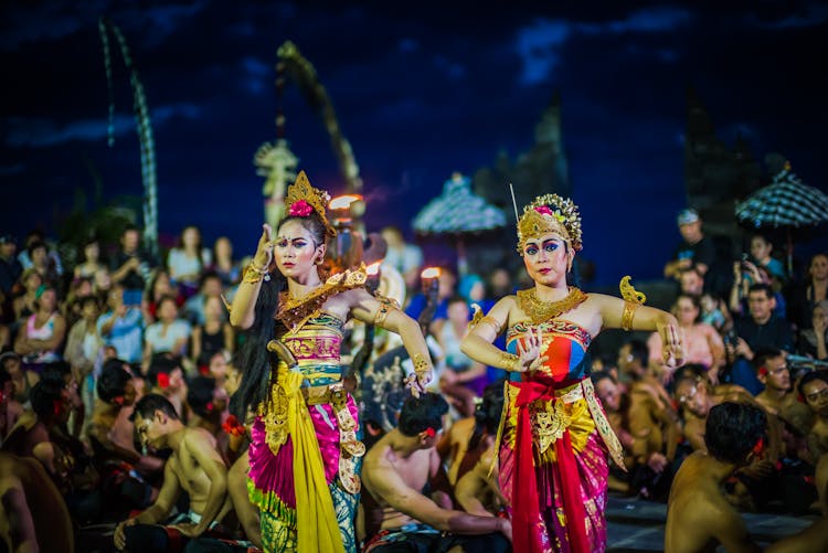 Two Women Dancing While Wearing Dresses At Night Time