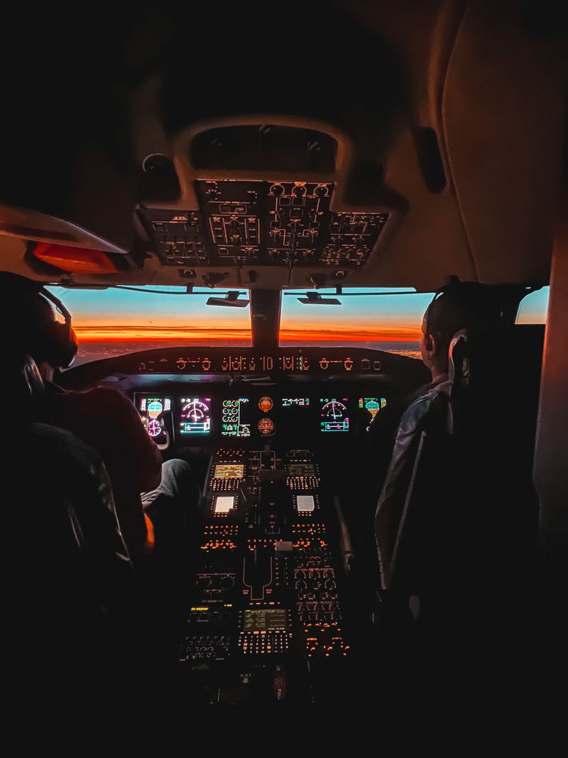Glowing cockpit interior of an airplane with pilots navigating through sunset skies