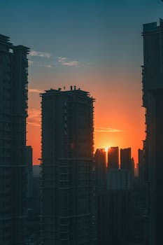 Dramatic city skyline at sunset with silhouetted skyscrapers and a vibrant sky.