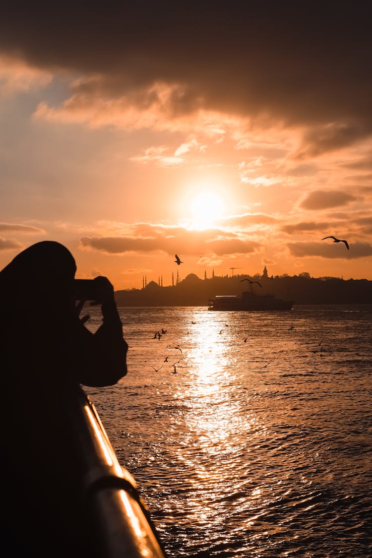 Person Photographing Sunset Above Sea