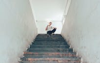 一名男子坐在城市环境的混凝土楼梯上，从低角度观看