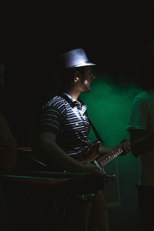 A Man in Stripe Shirt Playing Guitar