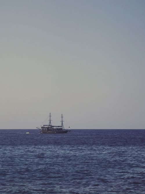 Free A classic old ship sailing on a tranquil sea under a clear blue sky. Stock Photo