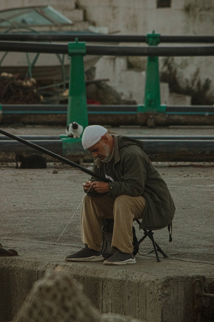 Man Sitting On A Stool And Fishing