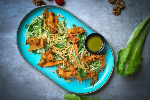 Free Colorful salad with crispy chicken on a blue plate, served with green dressing. Stock Photo