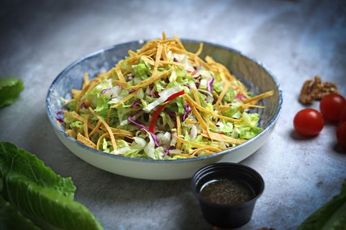 Free A vibrant vegetable salad topped with crispy strips and fresh dressing, perfect for healthy eating. Stock Photo