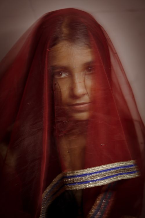Free A captivating portrait of a woman adorned with a red veil, conveying mystery and tradition. Stock Photo