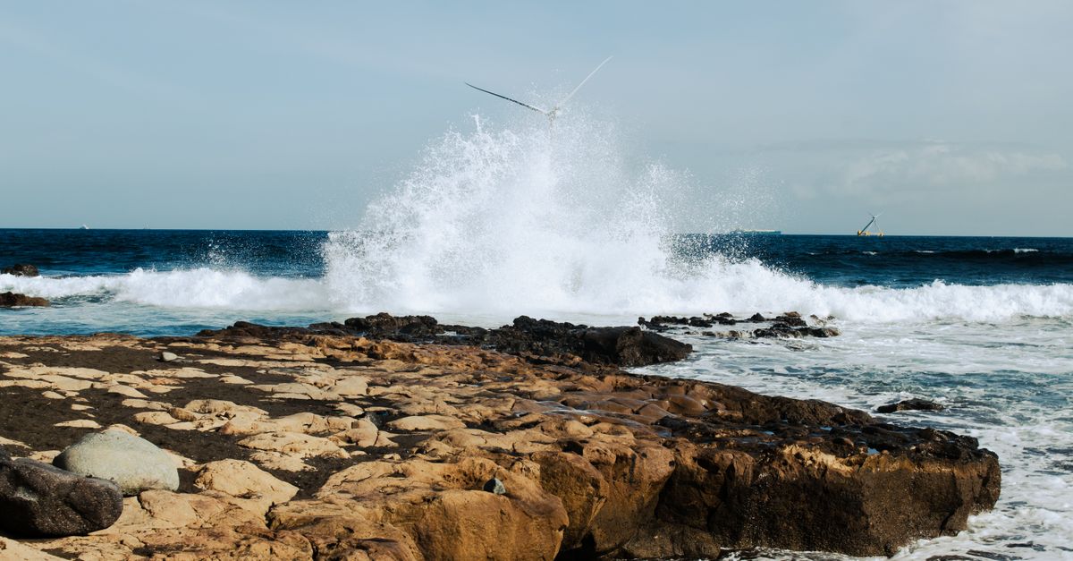 Photo by Annelies Brouw Powerful ocean waves crashing on a rocky shoreline, capturing nature's raw force and beauty.