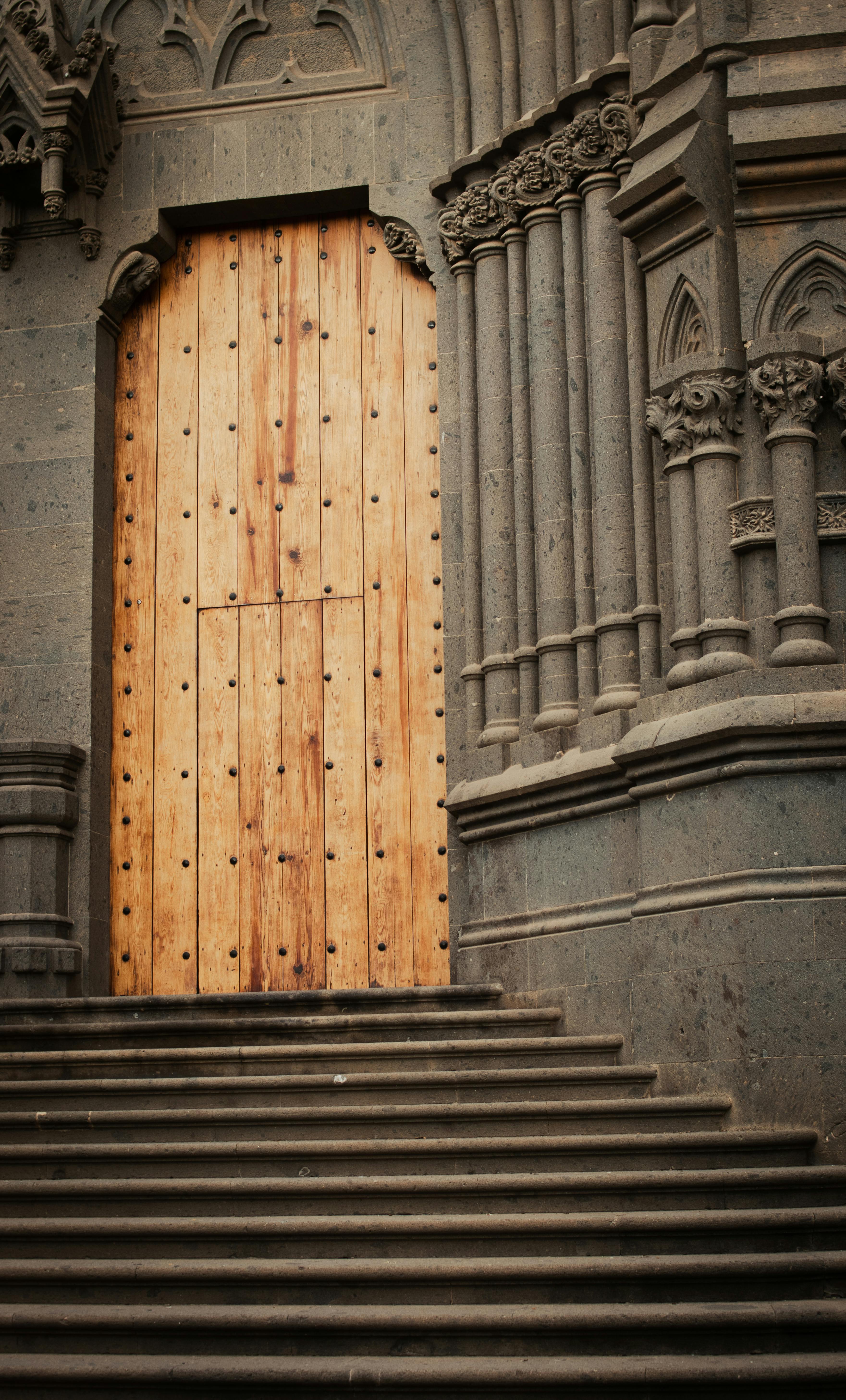 Close-up of a vintage wooden door with detailed stone carvings on a church facade.