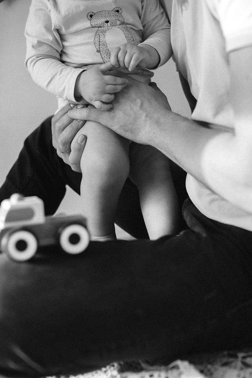 Free Black and white photo of a father bonding with his child, holding hands near a toy car. Stock Photo