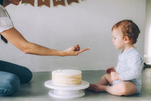 A baby experiencing his first birthday cake with a loving family member indoors.