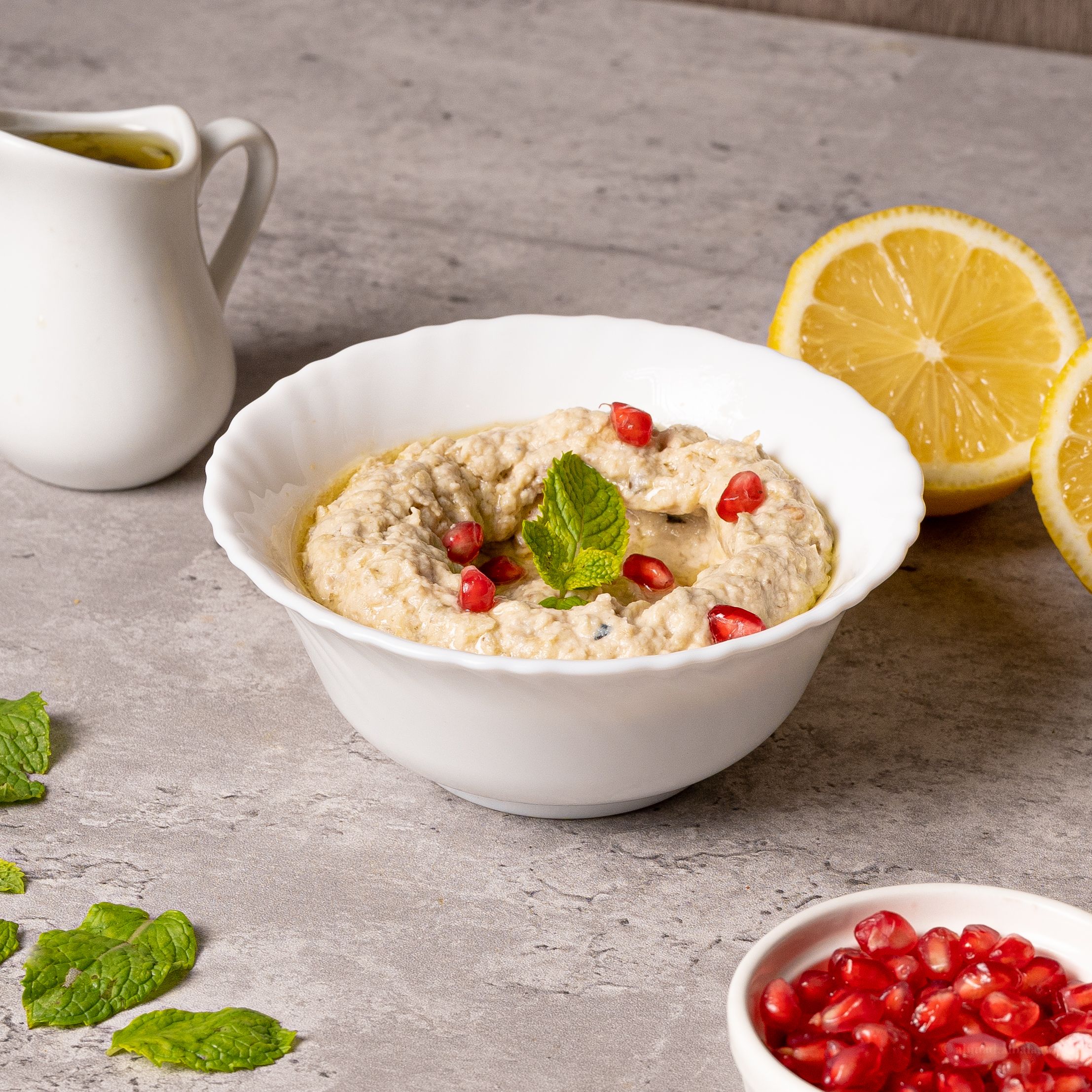 Creamy smoked spread in a white bowl with pomegranate and lemon — photo by Shameel mukkath on Pexels
