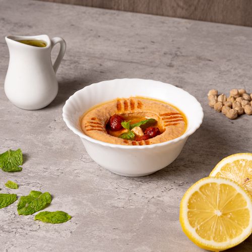 Free Delicious homemade hummus garnished with herbs and served with fresh lemons. Stock Photo