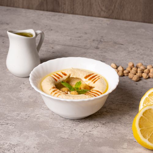 Free Delicious homemade hummus, topped with mint and served with fresh lemon slices on a concrete surface. Stock Photo