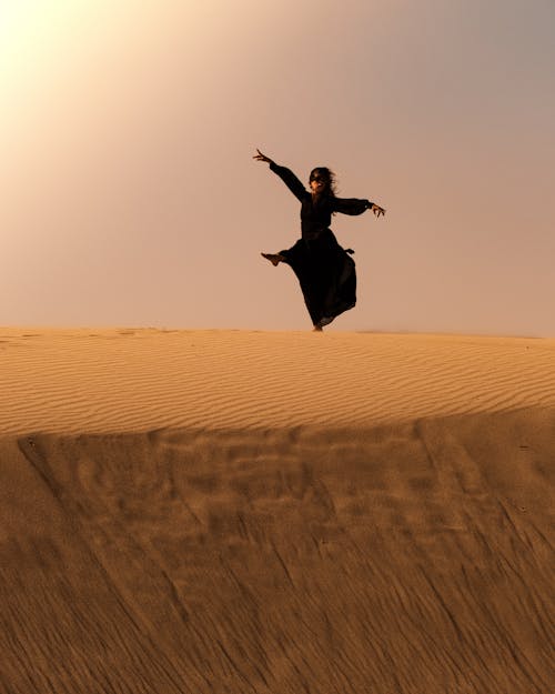 Jumping Woman in Black Dress on Desert