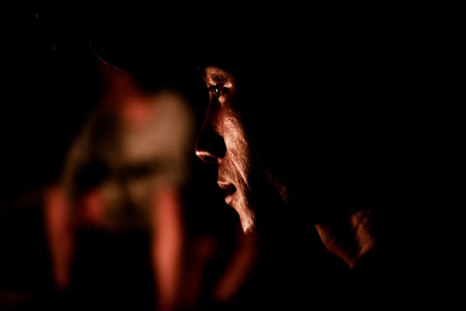 Intense side profile of a man in dark, dramatic lighting capturing emotion and mood.