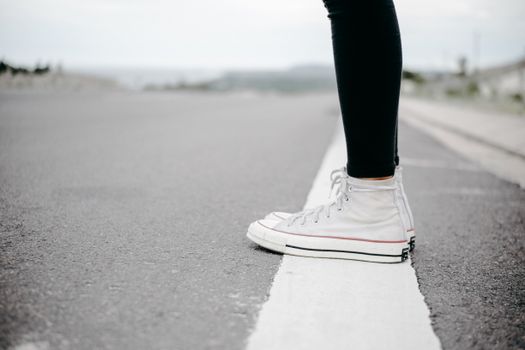 白色运动鞋在道路上的特写，凸显了休闲风格与旅行主题