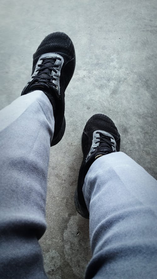 First Person Perspective Photo of a Person Sitting in Gray Trousers and Black Shoes 