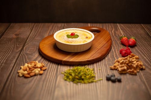Free A serving of creme brulee on a wooden board surrounded by nuts and berries. Stock Photo