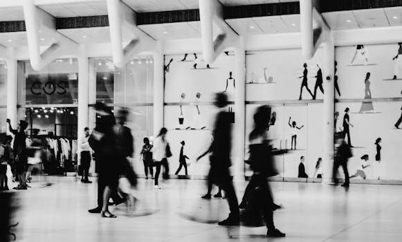 A bustling shopping scene with blurred figures in a modern black and white mall setting.