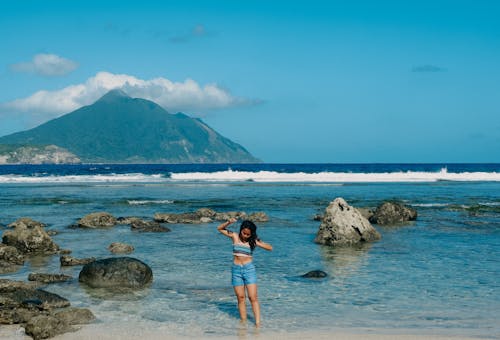 A Woman in Blue Short Standing at the Shore