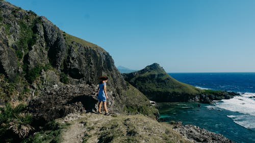 Woman Standing on Rocky Hills on Sea Coast