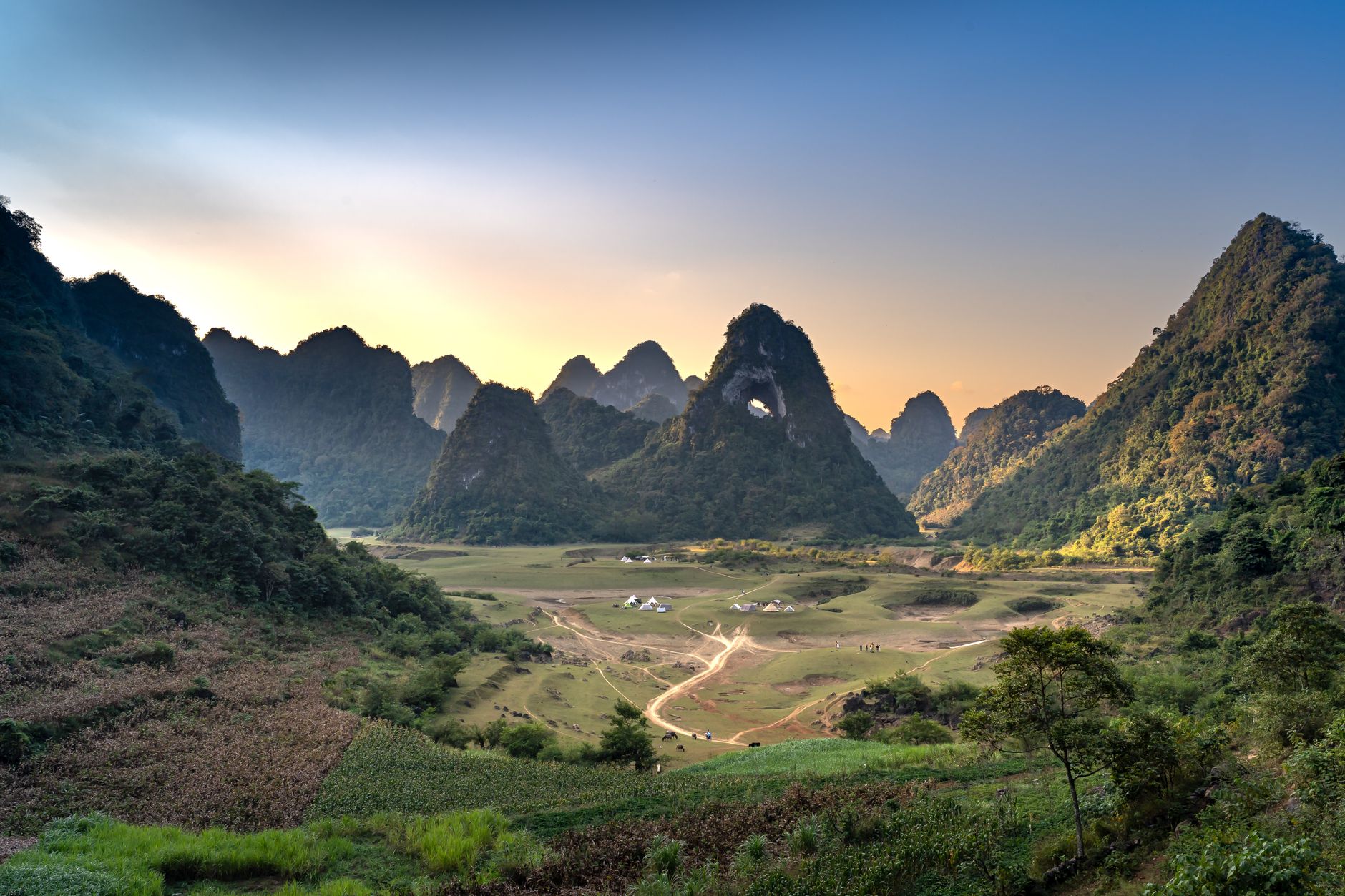 A breathtaking view of rugged mountains and lush valleys at sunset.