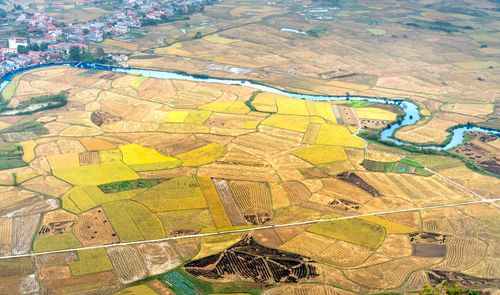 Free Stunning aerial shot of colorful patchwork farmlands bordered by a meandering river near a rural village. Stock Photo