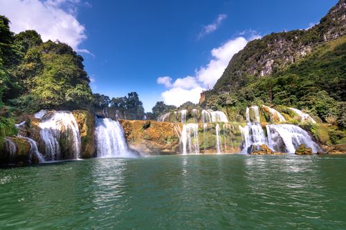 Free Serene waterfall landscape with lush greenery and clear blue sky, a perfect nature escape. Stock Photo