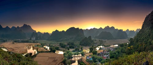 An Aerial Shot of a Farmland with a Silhouette of Mountains during the Golden Hour