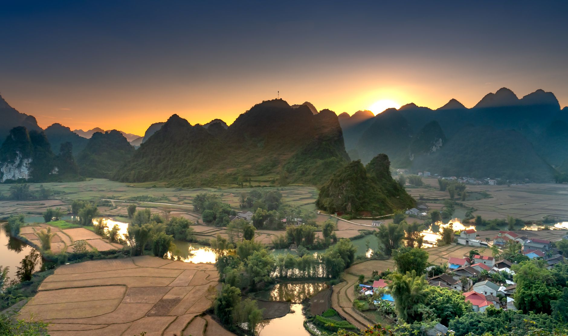 A breathtaking aerial view of Cao Bang, Vietnam at sunset with mountains, rivers, and fields.
