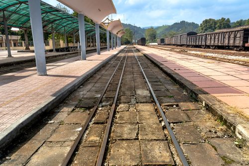 Free Deserted railway station platform with train tracks and hillside view, reflecting a serene travel moment. Stock Photo