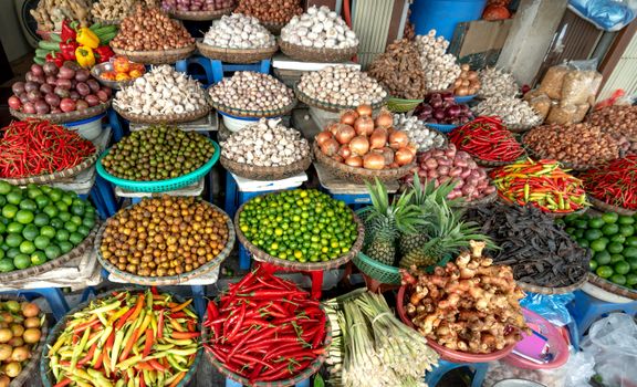 Colorful assortment of fruits, vegetables, and spices on display at an outdoor market.