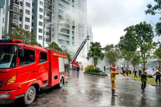 Firefighting operation at a high-rise apartment building, firefighters and trucks in action.